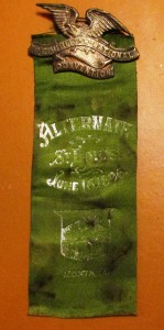 A green ribbon with the words " alternate st. Louis june 1 9 0 8."
