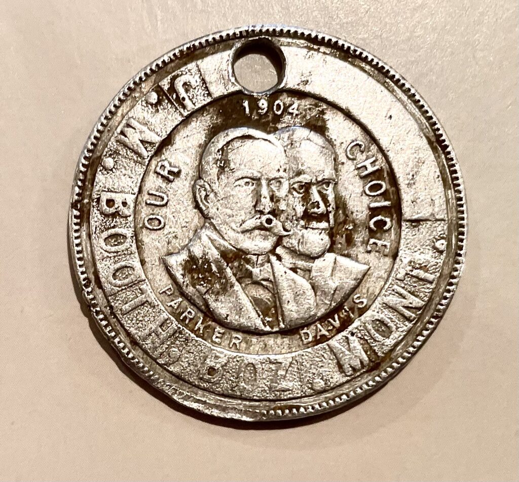 A silver medallion with two men on it.